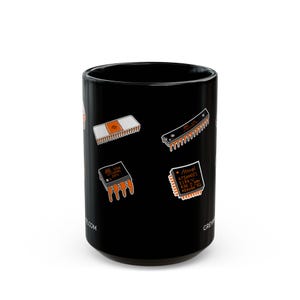 Puede incluir: Taza de cer&aacute;mica negra con ilustraciones naranjas y blancas de componentes electr&oacute;nicos. La taza tiene un acabado brillante y una forma cil&iacute;ndrica. Los textos "GREW" y "E.COM" son visibles en la taza.