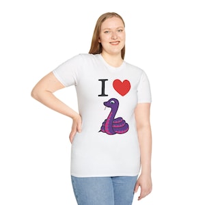 Może przedstawiać: Biała koszulka z motywem węża z kresk&oacute;wki. Koszulka ma napis "I <3" z czerwonym sercem i fioletowym wężem z r&oacute;żowymi kropkami. Wąż jest zwinięty i ma rozdwojony język.