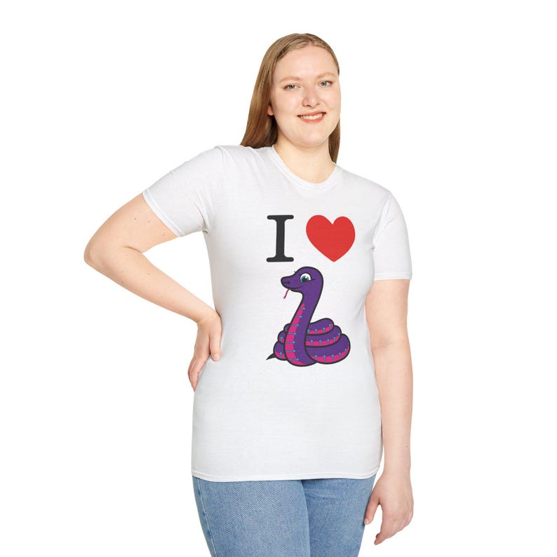 Może przedstawiać: Biała koszulka z motywem węża z kresk&oacute;wki. Koszulka ma napis "I <3" z czerwonym sercem i fioletowym wężem z r&oacute;żowymi kropkami. Wąż jest zwinięty i ma rozdwojony język.