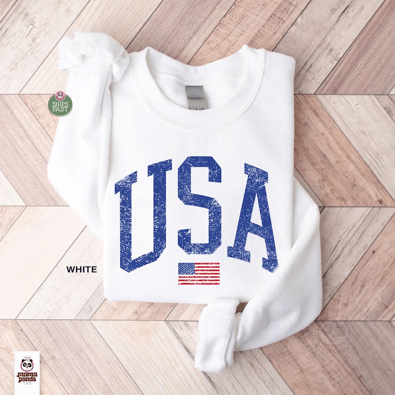 May include: White sweatshirt with the word "USA" in distressed blue lettering and a small American flag graphic. The word "WHITE" is printed below the sweatshirt.