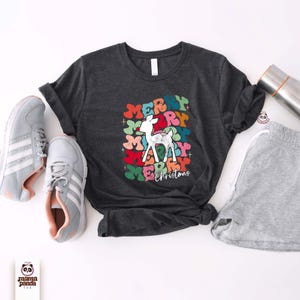 May include: A dark gray t-shirt with a colorful graphic of a reindeer and the text "Merry Christmas".