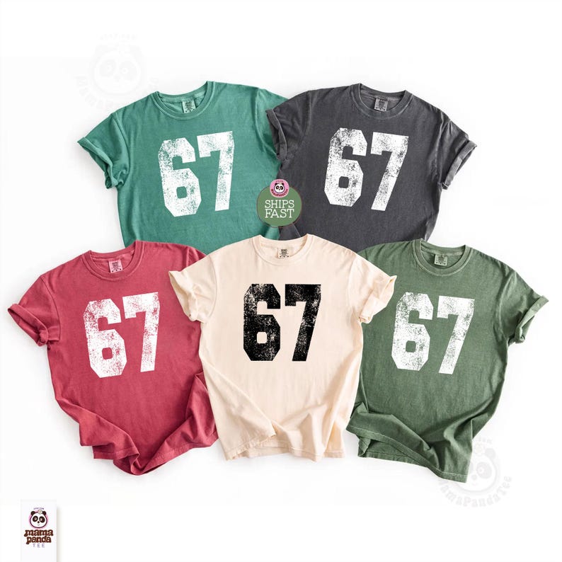 May include: Five short-sleeved t-shirts in various colors: red, green, beige, gray, and olive green. Each shirt features the number "67" in a distressed, white or black font. The shirts are displayed on a white background.