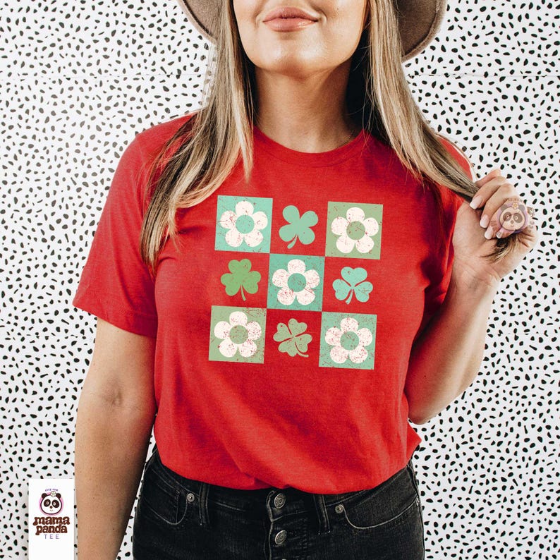 Op de afbeelding: Rood T-shirt met een groen en wit patroon van klavers en bloemen. Het patroon is in een raster van negen vierkanten.