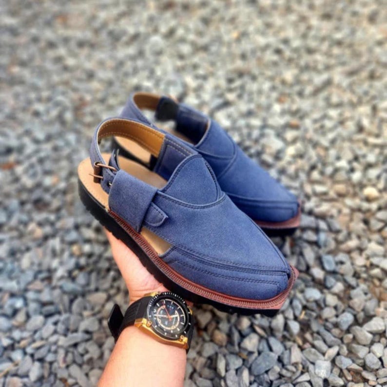 May include: A pair of blue leather sandals with a strap and buckle. The sandals have a brown sole and are made of a soft, comfortable material.