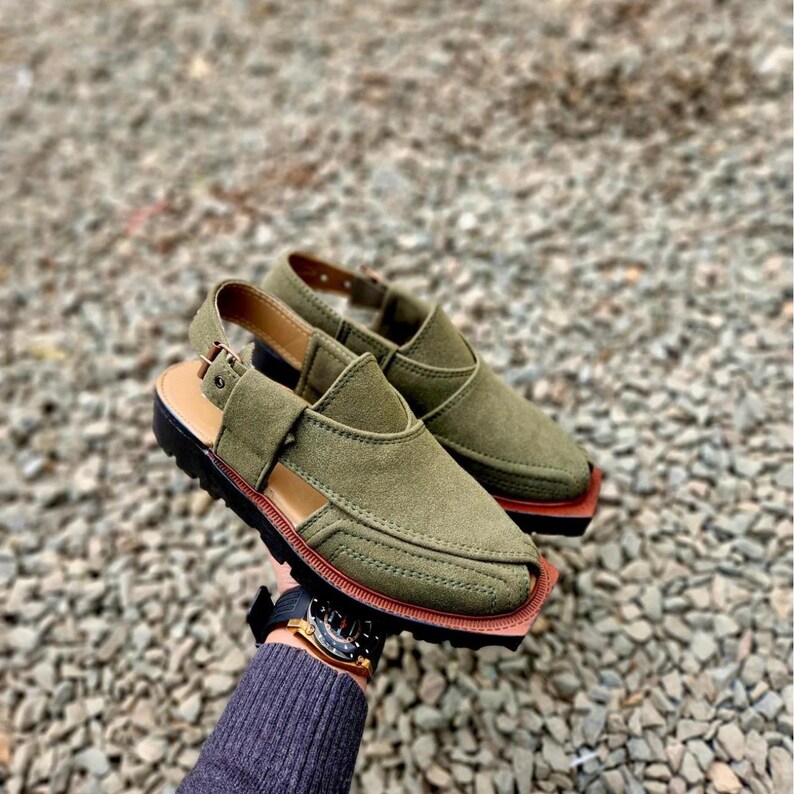May include: A pair of olive green leather sandals with a buckle strap and a pointed toe. The sandals have a brown sole and are made of a soft, comfortable material.