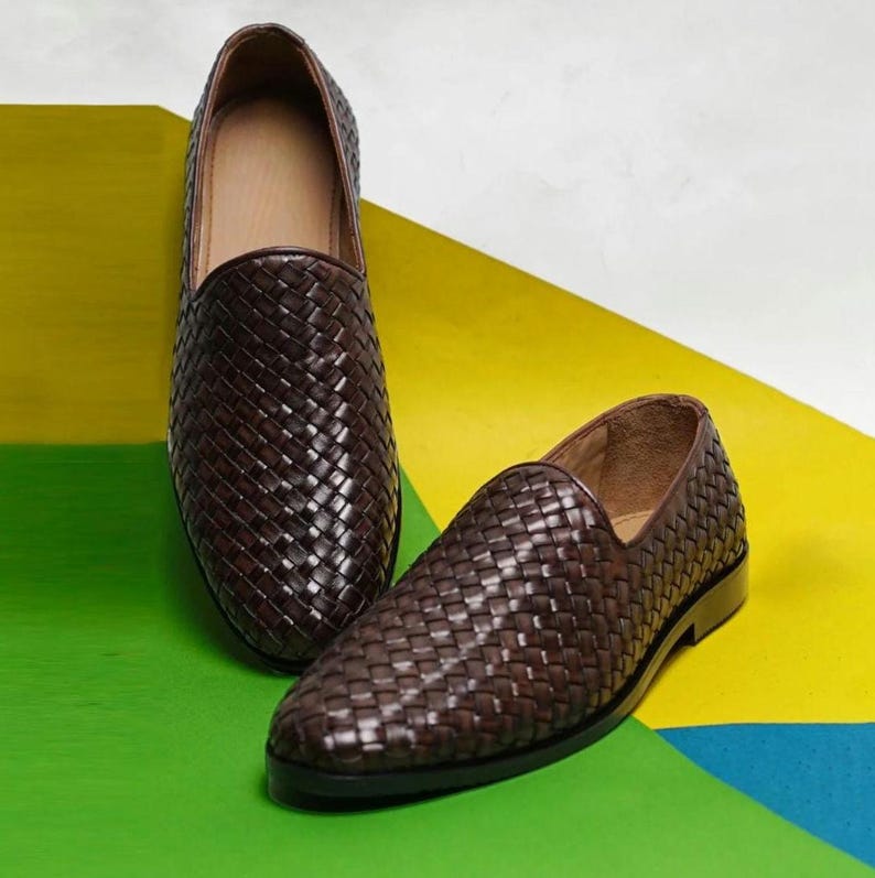 Pu&ograve; includere: Un paio di mocassini slip-on marrone scuro con tomaia in pelle intrecciata. Le scarpe presentano una punta arrotondata, un tacco basso e una fodera interna color cuoio. L'esterno &egrave; caratterizzato da un motivo a intreccio fitto e uniforme.