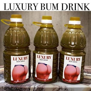 May include: Three large, clear plastic bottles filled with a green liquid. Each bottle has a yellow cap and a label that reads "LUXURY BUM DRINK" with an image of a pink buttock. The text "Visible Results in Few Days" is also on the label.