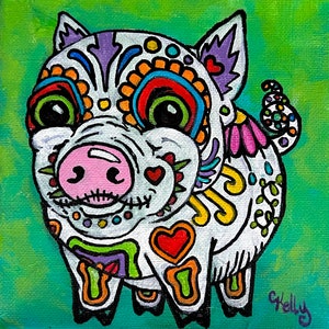 May include: A white pig with a pink snout and a colorful Day of the Dead sugar skull design. The pig has a purple ear and a pink wing on its back. The background is a bright green.