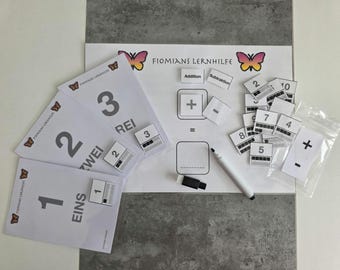 May include: Educational math learning set with cards and a whiteboard. Includes number cards, addition and subtraction symbols, and a whiteboard with a marker and eraser. The set features the text "FIOMIANS LERNHILFE".