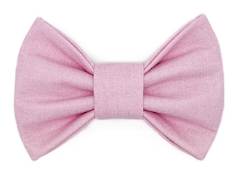 Peut inclure: Un nœud papillon rose clair avec un léger effet scintillant. Le nœud papillon est en tissu et a une forme classique en papillon. La bande centrale est de couleur rose clair uni.