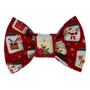 Op de afbeelding: Een rode kerststrik met een patroon van glazen potten met de kerstman, een rendier en kaarsen. De strik heeft een centrale knoop met een kaars en een poinsettia-ontwerp.