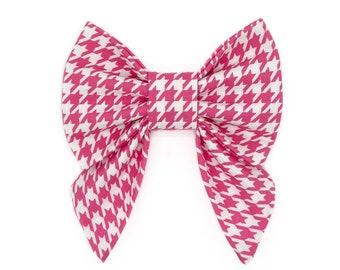 Op de afbeelding: Een grote, handgemaakte strik met een roze en witte pied-de-poule patroon. De strik is gecentreerd en heeft een klassieke vorm, met twee lussen en twee lange uiteinden. De stof is van gemiddeld gewicht en de strik is goed gemaakt.
