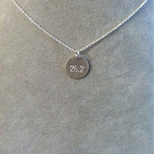 May include: A silver necklace with a round pendant that says "26.2" on it.