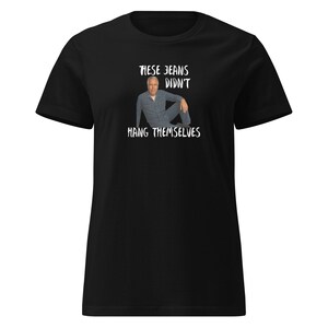 Może przedstawiać: Czarny t-shirt z białym napisem "THESE JEANS DIDN'T HANG THEMSELVES" oraz wizerunkiem mężczyzny w dżinsach. Koszulka ma okrągły dekolt.