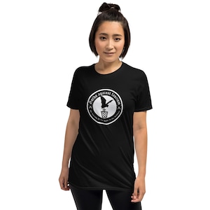 May include: A black t-shirt with a white circle graphic. The graphic features a bat flying out of a trash can with the text "Goths Against Fascism" around the outside. The text "The diversity we fight for begins in our hearts" is written in a smaller font below the circle.