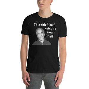 Puede incluir: Una camiseta negra con un gráfico blanco de la cara de un hombre y el texto "Esta camiseta no se va a colgar sola".