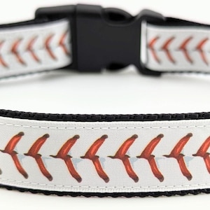 May include: White dog collar with a baseball stitch pattern. The stitching is red and white.