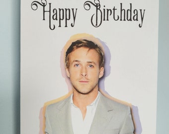 Op de afbeelding: Een witte kaart met de tekst "Ryan wenst je een gelukkige verjaardag" in zwarte cursieve letters. Op de achtergrond is een foto van Ryan Gosling in een lichtgrijs pak te zien.
