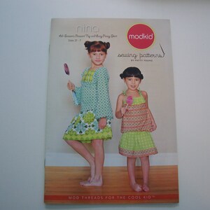 May include: A magazine cover featuring two girls wearing dresses. The magazine is titled "nina" and "modkid sewing patterns by Patty Young". The cover also includes the text "All-Seasons Peasant Top and Baby Dress Size 2T-7".