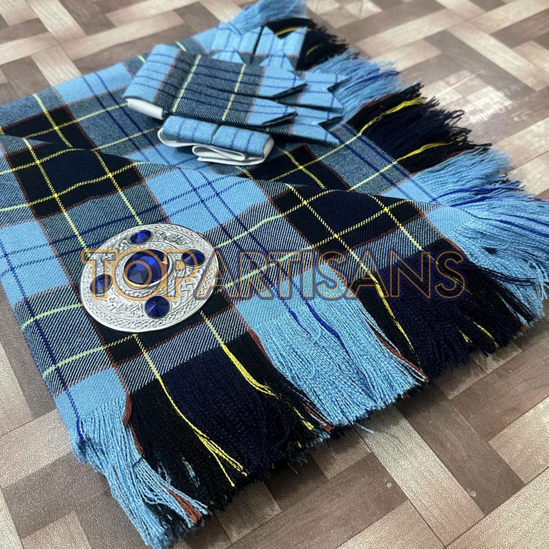 May include: A blue tartan kilt with a matching sash and a decorative silver brooch. The kilt features a classic plaid pattern in shades of blue, black, and yellow. The fringe adds a traditional touch. The text "TOP ARTISANS" is visible.