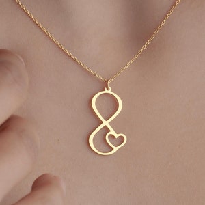 May include: A gold necklace with an infinity symbol pendant that has a small heart inside the loop.