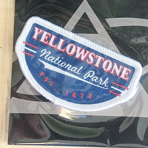 Puede incluir: Parche bordado blanco y azul con texto rojo que dice "Yellowstone National Park Est. 1872".