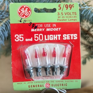 May include: A pack of 3.5 volt Christmas lights for 35 and 50 light sets. The pack is red and green and features the General Electric logo. The lights are clear with red tips and are labelled "Merry Midget".