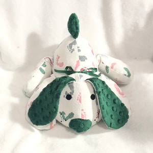 May include: A green and white plush dog toy with a footprint pattern. The dog has a green nose and ears.