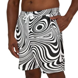 Puede incluir: Pantalones cortos de baño con estampado en blanco y negro. Los pantalones cortos presentan un diseño arremolinado repetitivo. Tienen cintura con cordón y bolsillos. El patrón crea una ilusión óptica. Los pantalones cortos son de material ligero.
