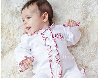 May include: A white baby onesie with red ruffled trim and a monogrammed "M.S.S." embroidered on the front.