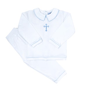 May include: White baby outfit with a blue trim and a cross embroidered on the shirt.
