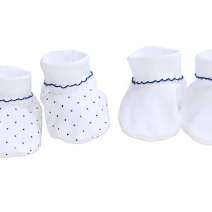 May include: A set of four baby booties in white with blue trim. Two booties have a blue polka dot pattern.