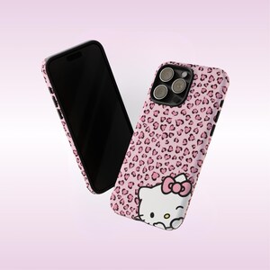 May include: Two pink phone cases with a black border. One case features a pink leopard print pattern, and the other case has the same pattern with a Hello Kitty graphic. The phone screens are black.