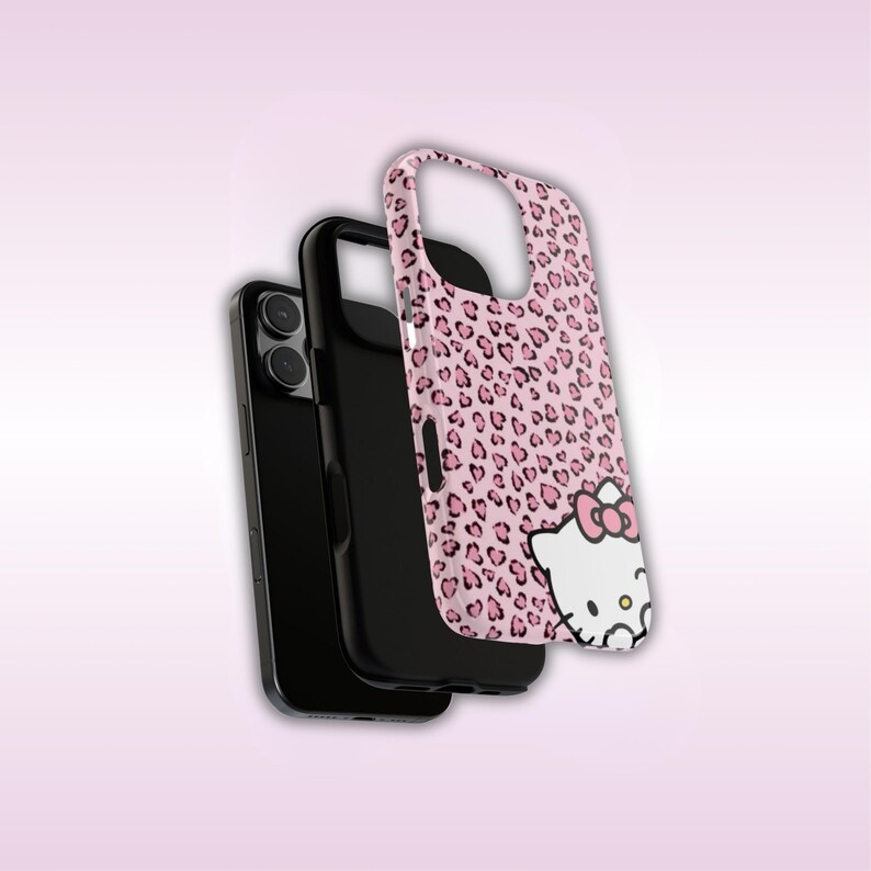 May include: A pink phone case with a leopard print design and a Hello Kitty graphic. The case is shown with a black phone and a black phone case.