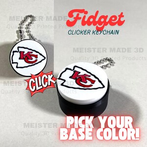 May include: A 3D printed keychain with a red, white, and black Kansas City Chiefs logo. The keychain is a fidget clicker and has a black base. The text "Fidget Clicker Keychain" and "Pick Your Base Color!" is visible in the image.