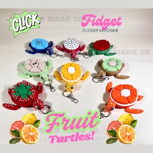 May include: Seven colorful 3D printed fruit-shaped turtle keychains. Each keychain features a different fruit design, including watermelon, pineapple, kiwi, orange, lemon, strawberry, and a black and white polka dot design. The keychains are labeled "Fidget Clicker Keychain" and "Fruit Turtles!"