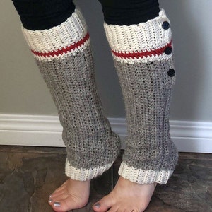 May include: Grey, white and red crocheted leg warmers with buttons. The leg warmers are folded down at the top to show the white and red trim.