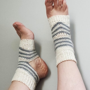 Puede incluir: Un par de calcetines de tobillo de crochet blanco con rayas grises. Los calcetines tienen un diseño de talón abierto.
