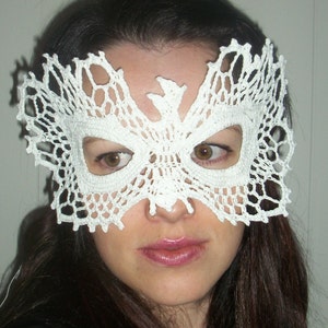 May include: A white crocheted lace masquerade mask with intricate details. The mask covers the eyes and nose, leaving the mouth visible.