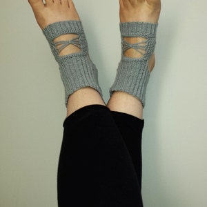 Puede incluir: Un par de calcetines de tobillo de punto gris con un diseño de cruz en el tobillo.