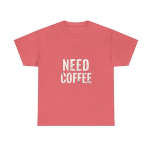 May include: A coral pink t-shirt with the text "NEED COFFEE" printed in white with a distressed look.