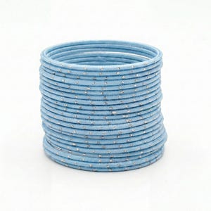 May include: A stack of light blue bangles with silver flecks. The bangles are round and appear to be made of metal. The stack is centered on a white background.