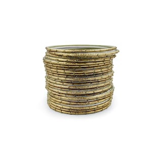 May include: A pile of gold-coloured bangles. Each bangle is thin and decorated with small, evenly spaced details. The bangles are stacked neatly, creating a layered effect. The background is plain white.