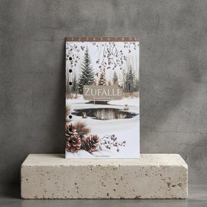 Könnte beinhalten: Ein rechteckiges Planer-Einlageblatt mit einer winterlichen Waldszene, Tannenbäumen, einem zentralen Teich und braunen Tannenzapfen am unteren Rand. Die Oberkante zeigt die Zahlen 1 bis 10 und in der Mitte steht der Text ZUFÄLLE in einem braunen Kasten.