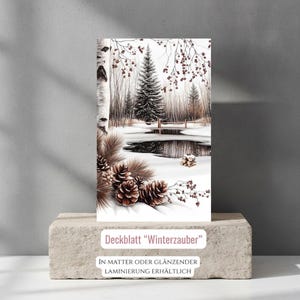 Könnte beinhalten: Eine rechteckige Karte mit einer Winterlandschaftsillustration, die einen verschneiten Teich, Tannen und Birkenrinde zeigt. Im Vordergrund sind braune Tannenzapfen und Nadeln zu sehen. Der Text lautet Deckblatt Winterzauber und In matter oder glänzender Laminierung erhältlich.