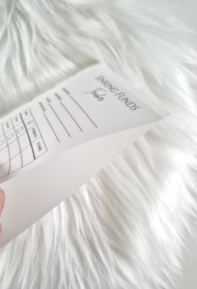 May include: A white paper sinking funds tracker sheet with black printed text and lines. The document features the header SINKING FUNDS Tracker, followed by columns for date, description, and amount, with checkboxes for tracking financial progress.