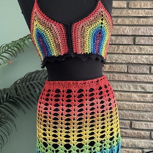 May include: A rainbow crochet top and skirt set. The top is a halter style with a black trim. The skirt is a mini skirt with a scalloped hem.