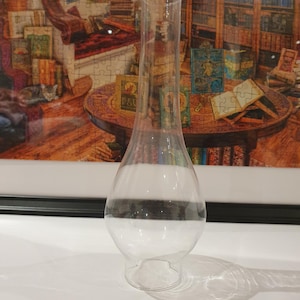 Puede incluir: Una chimenea de lámpara de vidrio transparente con un bulbo redondeado y una base ancha. La chimenea está diseñada para usarse con lámparas de aceite.