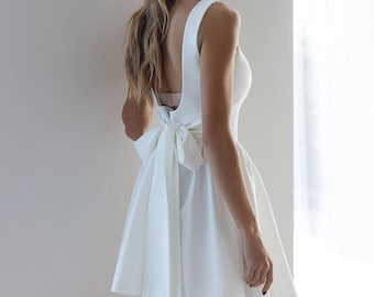 Vestido de novia corto con espalda descubierta y lazo llamativo: minivestido para novias modernas, perfecto para ensayos, compromisos y despedidas de soltera.