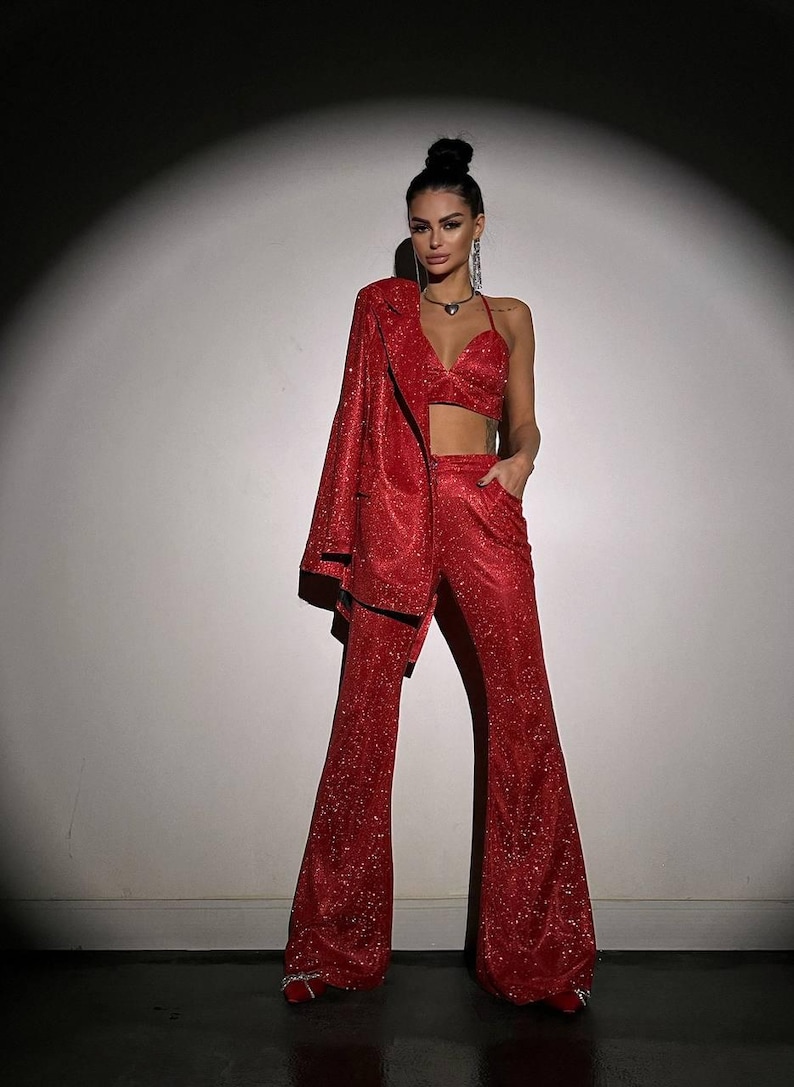 May include: A red sparkly blazer and pants set. The blazer has a notched lapel and long sleeves. The pants are wide-legged and have a high waist.
